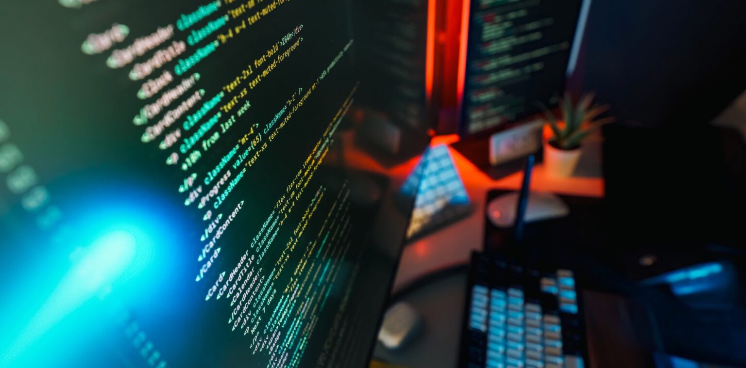 Cinematic overhead shot of a moody, neon-lit developer desk with Next.js React component code glowing on screen
